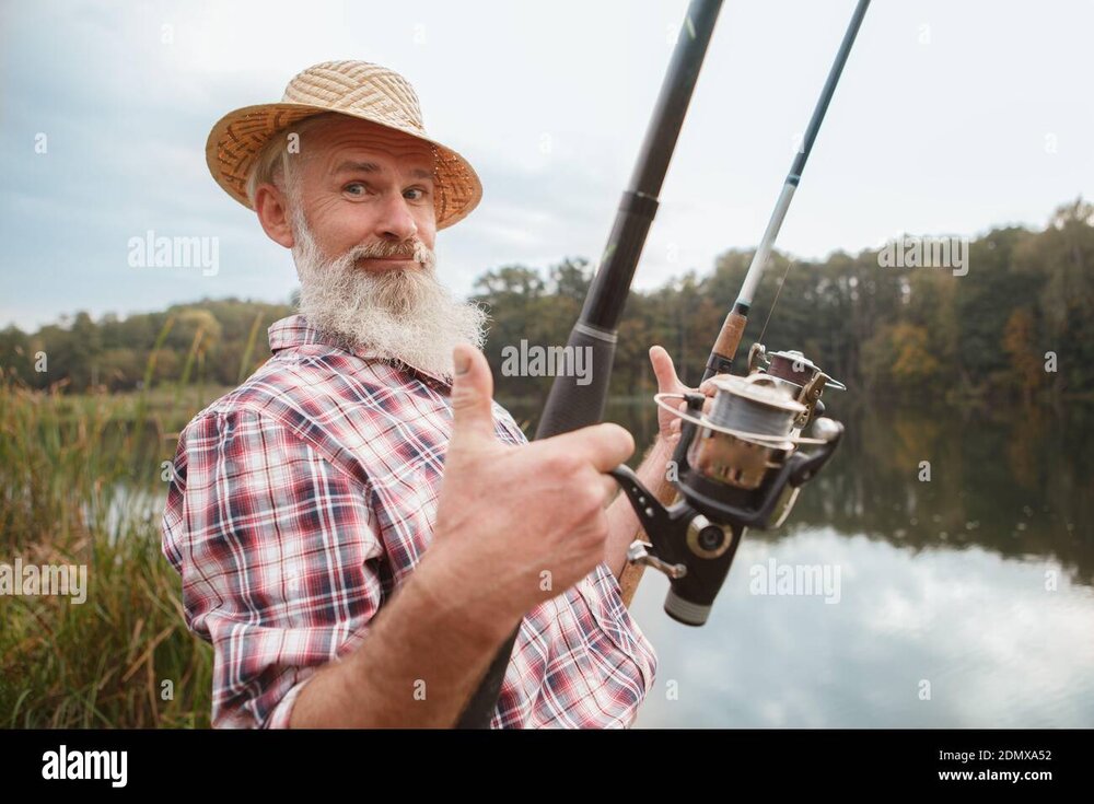 happy-senior-fisherman-smiling-showing-thumbs-up-fishing-with-two-rods-2DMXA52.jpg